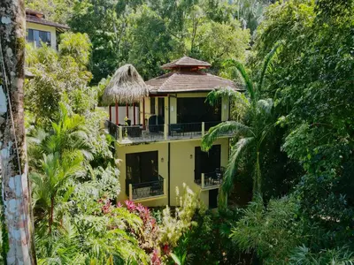 a yellow building in the middle of a garden at Villas by Tekoa in Uvita