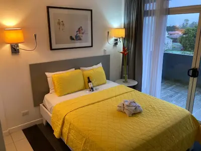 a bedroom with a bed with a yellow blanket and lamps at Apartahotel Altos de la Sabana in San José