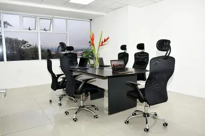 an office with a desk with chairs and a laptop at Apartahotel Altos de la Sabana in San José