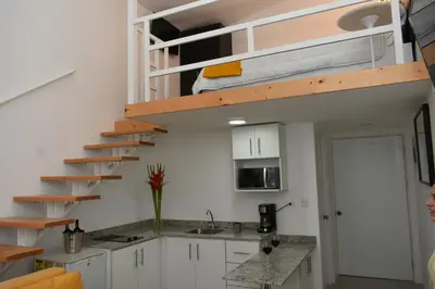 a kitchen with white cabinets and a loft bed at Apartahotel Altos de la Sabana in San José