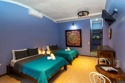 a bedroom with two beds and a table and a desk at Hotel Arte Natura in Fortuna