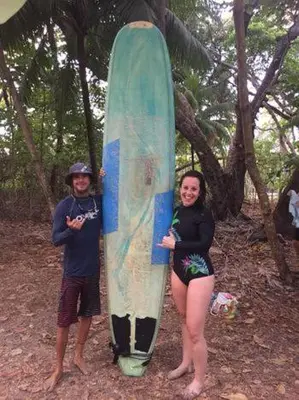 a man and a woman standing next to a surfboard at Beach Break Santa Teresa Apartamentos in Santa Teresa Beach