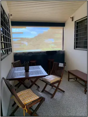 a patio with a table and chairs and a screen at Beach Break Santa Teresa Apartamentos in Santa Teresa Beach