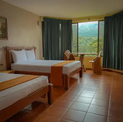 a hotel room with two beds and a large window at Arenal Roca Lodge & Bungalows in Fortuna