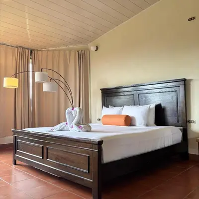 a bedroom with a large bed with a wooden headboard at Arenal Roca Lodge & Bungalows in Fortuna