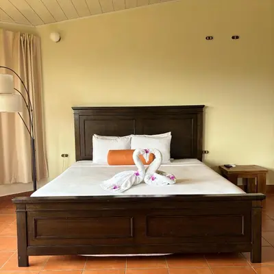 a bed with a wooden headboard with towels on it at Arenal Roca Lodge & Bungalows in Fortuna