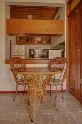 a dining room table with two chairs and a kitchen at Apartotel Girasol in Jacó
