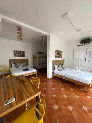 a room with two beds and a table and chairs at Hotel Pura Natura Beachfront Tortuguero in Tortuguero