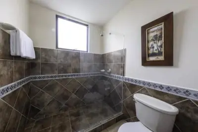 a bathroom with a toilet and a shower and a window at 777J Beachfront Luxury Condo 3 BR/2.5BA Near SJO - Jaco Beach in Jacó