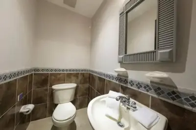 a bathroom with a toilet and a sink and a mirror at 777J Beachfront Luxury Condo 3 BR/2.5BA Near SJO - Jaco Beach in Jacó