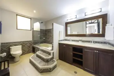 a bathroom with a sink toilet and a mirror at 777J Beachfront Luxury Condo 3 BR/2.5BA Near SJO - Jaco Beach in Jacó