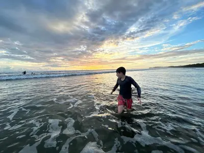 a young man walking in the water on the beach at Casa Linda in Uvita