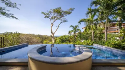 an infinity pool with a hot tub next to a resort at Villa Zindagi Luxury Villa Private Pool - Reserva Conchal in Playa Conchal