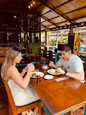 a man and woman sitting at a table eating food at Ávita Lodge in Quesada