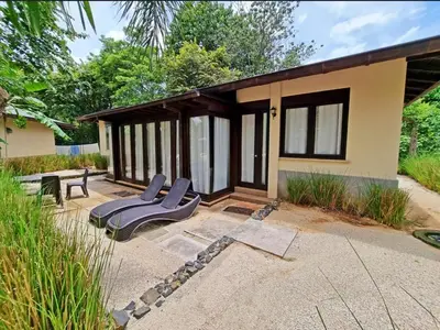 a house with two lounge chairs on a patio at Beach Walk Costa Rica in Playa Avellana