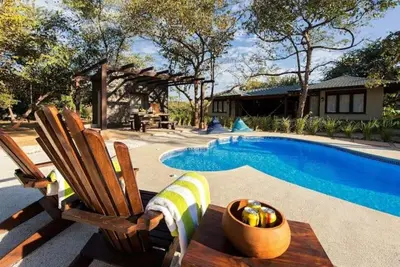 a pool with two chairs and a bowl of fruit next to it at Beach Walk Costa Rica in Playa Avellana