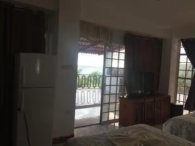 a room with two beds and a refrigerator and a balcony at Hotel Coco Beach in Manuel Antonio