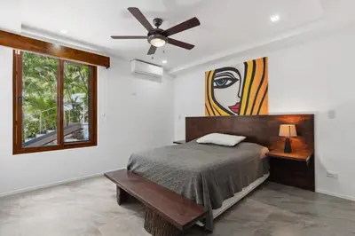 a bedroom with a bed and a painting on the wall at 5-BD Beachfront, Ocean-View Hillside Home in Playa Flamingo