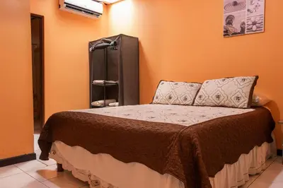 a bedroom with a bed with an orange wall at Marta's Guesthouses, apartamentos con entrada autonoma in Puerto Limón