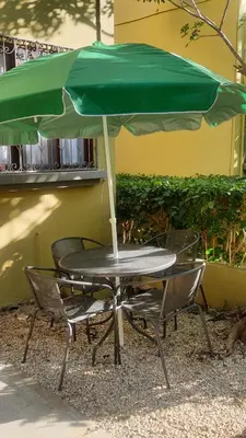 a table and chairs with a green umbrella at La Casita de Naomi in Tamarindo