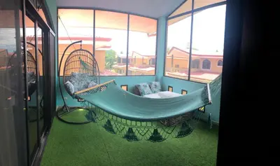 a swinging hammock in a room with windows at Family oriented house just steps to the beach in Jacó