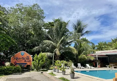 a resort with a swimming pool and palm trees at Family oriented house just steps to the beach in Jacó