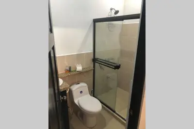 a bathroom with a toilet and a glass shower at Family oriented house just steps to the beach in Jacó