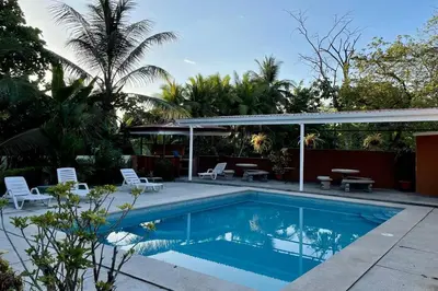 a swimming pool with a patio and a house at Family oriented house just steps to the beach in Jacó