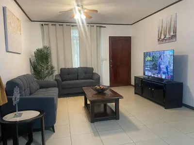a living room with couches and a flat screen tv at Family oriented house just steps to the beach in Jacó