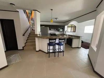 a kitchen with a counter and two bar stools at Family oriented house just steps to the beach in Jacó