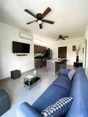 a living room with a blue couch and a ceiling fan at Hermoso Condominio en el Centro de Jaco Lapa Living in Jacó