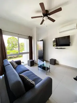 a living room with a blue couch and a ceiling fan at Hermoso Condominio en el Centro de Jaco Lapa Living in Jacó