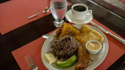 a plate of food with sausage and bread and a cup of coffee at Orquideas Boutique Hotel in Fortuna