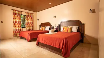 a bedroom with two beds with red sheets and a window at Orquideas Boutique Hotel in Fortuna