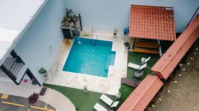 an overhead view of a swimming pool with chairs and a house at Apartamentos Ganesha Jacó in Jacó