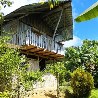 a wooden building with a balcony on top of it at La Muñequita Lodge 1 - culture & nature experience in Palmar Norte