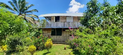 a wooden house with a balcony in a garden at La Muñequita Lodge 1 - culture & nature experience in Palmar Norte