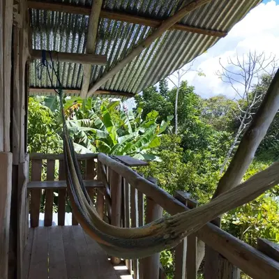a hammock on a porch of a house at La Muñequita Lodge 1 - culture & nature experience in Palmar Norte