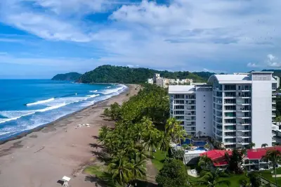 a view of a beach with buildings and the ocean at Luxury Oceanfront Stay, Two Master Suites, Walk to Town in Jacó