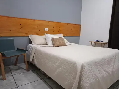 a bedroom with a large white bed and a chair at Hotel Cañas in Cañas