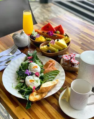 a table with a plate of breakfast food and a drink at Makanda by The Sea Hotel Adults Only in Manuel Antonio