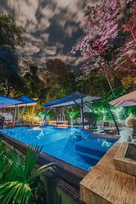 a large swimming pool with tables and umbrellas at Makanda by The Sea Hotel Adults Only in Manuel Antonio
