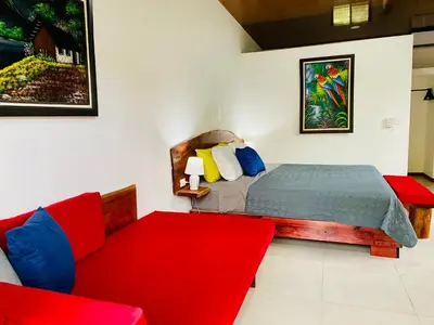 a bedroom with a bed and a red couch at Casa Antema Tamarindo, maison luxe, piscine, jungle, yoga, gym in Tamarindo
