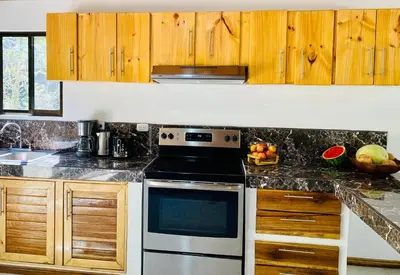 a kitchen with wooden cabinets and a stove top oven at Casa Antema Tamarindo, maison luxe, piscine, jungle, yoga, gym in Tamarindo