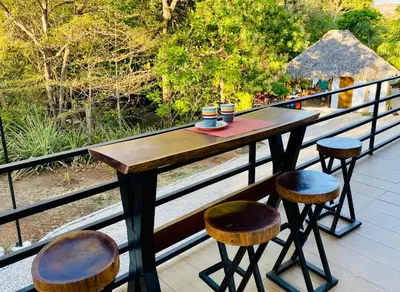 a wooden table and stools sitting on a balcony at Casa Antema Tamarindo, maison luxe, piscine, jungle, yoga, gym in Tamarindo