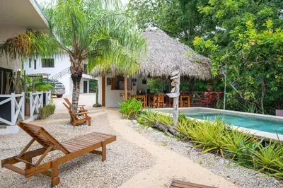 a resort with a pool and chairs and a house at Casa Antema Tamarindo, maison luxe, piscine, jungle, yoga, gym in Tamarindo