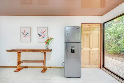 a refrigerator in a room with a table and a window at Casa Antema Tamarindo, maison luxe, piscine, jungle, yoga, gym in Tamarindo
