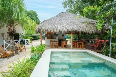 a villa with a swimming pool and a hut at Casa Antema Tamarindo, maison luxe, piscine, jungle, yoga, gym in Tamarindo