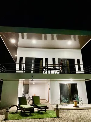 a man standing on the balcony of a house at Casa Antema Tamarindo, maison luxe, piscine, jungle, yoga, gym in Tamarindo