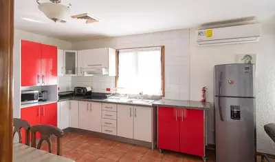 a kitchen with red and white cabinets and a refrigerator at Pura Vida Villa! Beachfront Golf and Country Club Los Delfines 24 hours security in Tambor